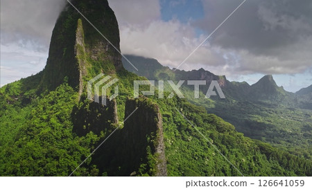 Aerial drone flight over mountain stone ridge. Green rainforest blanket majestic hills under vibrant sky. Breathtaking beauty of Moorea, French Polynesia. Remote wild nature exotic travel background 126641059