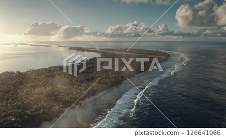 A stunning aerial perspective captures a pristine tropical island surrounded by turquoise waters. Waves gently lap at the shore as the sun sets, casting a warm glow over the lush greenery. A stunning aerial perspective captures a pristine tropical island surrounded by turquoise waters. Waves gently lap at the shore as the sun sets, casting a warm glow over the lush greenery. 126641066