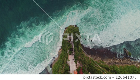 Turquoise waves crashing on rocky Bali cliff with temple ruins, aerial drone view from above showing the power of nature and the beauty of Indonesian landscape Turquoise waves crashing on rocky Bali cliff with temple ruins, aerial drone view from above showing the power of nature and the beauty of Indonesian landscape 126641073