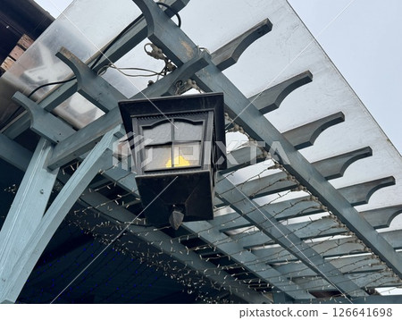 A black street lamp hangs on the roof of a veranda in summer, close-up. High quality photo A black street lamp hangs on the roof of a veranda in summer, close-up. High quality photo 126641698