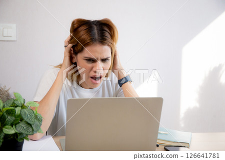 Unhappy young caucasian businesswoman using laptop computer on desk with stress and burnout. Unhappy young caucasian businesswoman using laptop computer on desk with stress and burnout. 126641781