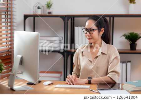 Happiness young businesswoman using desktop computer on desk in living room at home office. Happiness young businesswoman using desktop computer on desk in living room at home office. 126641804