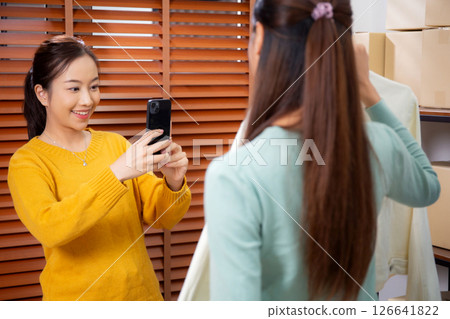 Two asian woman taking picture of clothes for online store. Two asian woman taking picture of clothes for online store. 126641822