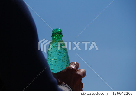 Person is holding a green bottle of water Person is holding a green bottle of water 126642203