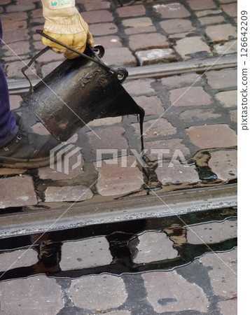 Man is pouring black liquid into a bucket 126642209