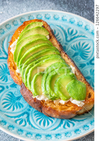 Toasted white bread with labneh spread and avocado slices on blue plate 126642297