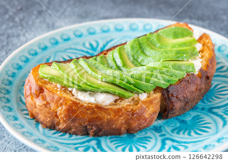 Toasted white bread with labneh spread and avocado slices on blue plate 126642298