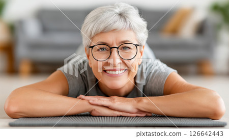 Smiling caucasian mature female relaxing on yoga mat indoors 126642443