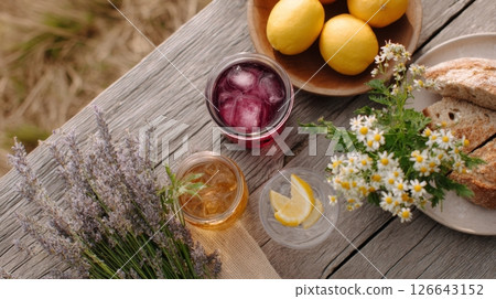 Savor delicious jam jar cocktails and fresh fruits during a relaxing picnic in a vibrant countryside setting 126643152