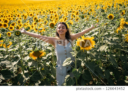 Happy woman arms raised and enjoying in sunflower field. 126643452
