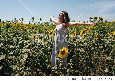 Happy woman arms raised and enjoying in sunflower field. 126643465