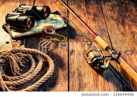 Fishing composition with spinning rod and binoculars. Spinning rod with reel on wooden background. 126644490