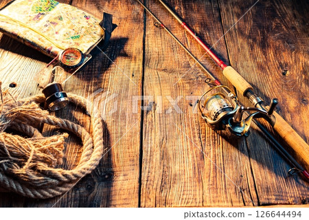 Fishing composition. Fishing rod on wooden background. Rope and spinning rod View from an angle. 126644494