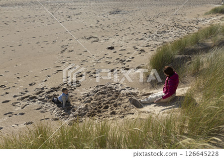 Mother and son playing on a sandy beach by the dunes Mother and son playing on a sandy beach by the dunes 126645228