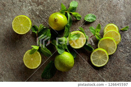 Slices of lime and sprigs of fresh mint on a wet stone table. Slices of lime and sprigs of fresh mint on a wet stone table. 126645597