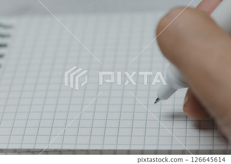 Woman Hand's Writing on a Grid Notebook with a White Pen 126645614