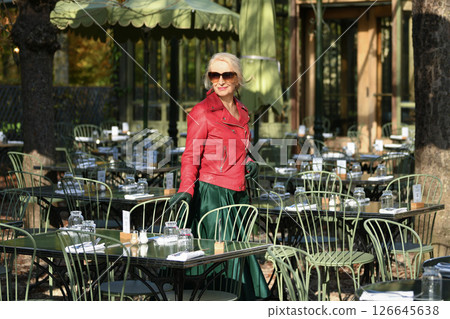 Gray-haired woman in her sixties in a red leather jacket in a restaurant in a Paris Gray-haired woman in her sixties in a red leather jacket in a restaurant in a Paris 126645638