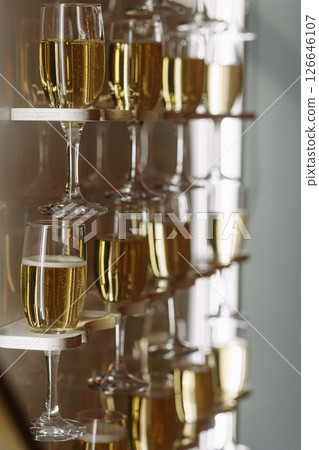 Glasses of champagne on modern wall-mounted shelf with reflections and soft light indoors 126646107
