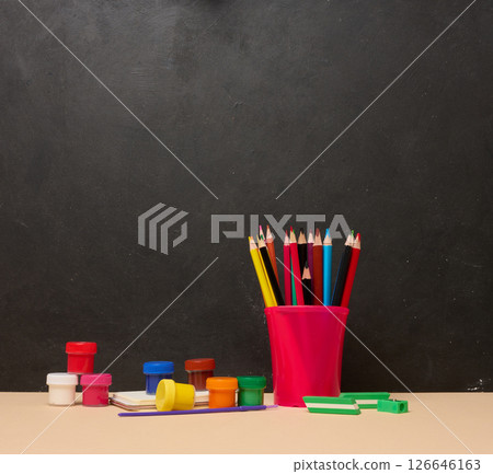 Pink glass with writing utensils, paint cans, brush, creativity or school activities Pink glass with writing utensils, paint cans, brush, creativity or school activities 126646163