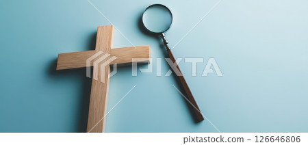 Wooden cross and magnifying glass on blue surface Wooden cross and magnifying glass on blue surface 126646806
