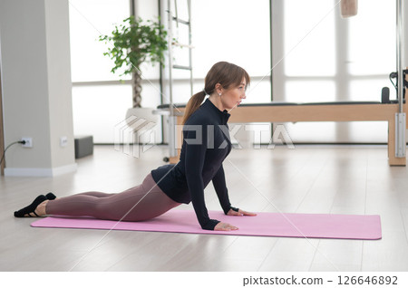 Concentrated woman doing pilates in studio alone.  126646892