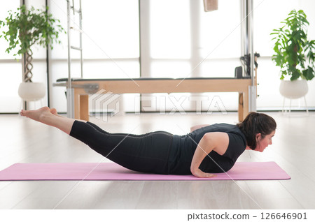 A plump woman does Pilates in a studio. A plump woman does Pilates in a studio. 126646901