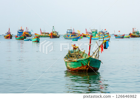 Colorful wooden fishing boats floating in the calm waters of Vietnamese harbor, early morning light 126646982