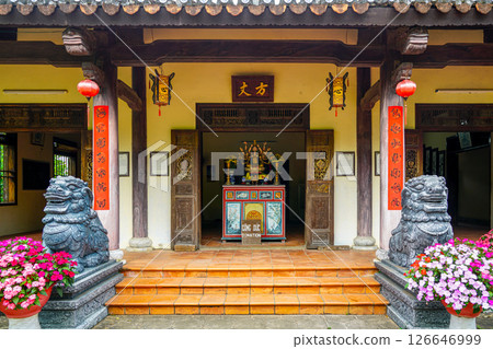 Entrance of a traditional Vietnamese temple with guardian lion statues, lanterns, and donation altar 126646999