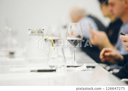 Filled Glass with Red Wine on Table During Degustation. Focused Wine Tasting in Progress, Close up Indoor. Filled Glass with Red Wine on Table During Degustation. Focused Wine Tasting in Progress, Close up Indoor. 126647275