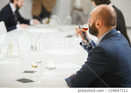 Sommelier Tasting Untitiled Whiskey being in Training. Professional Tasting Focus: Expert Sommeliers Spirits Analysis.  Sommelier Tasting Untitiled Whiskey being in Training. Professional Tasting Focus: Expert Sommeliers Spirits Analysis.  126647311
