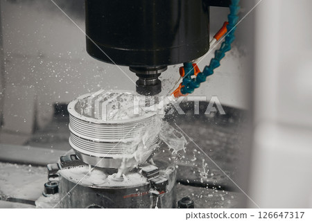 CNC milling machine cutting aluminium automotive part with a coolant liquid. Hi-Technology manufacturing process.  126647317