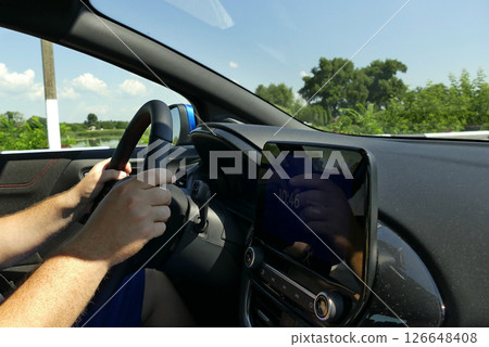 Driver hands in correct position on a steering wheel inside car on speed at highway  126648408