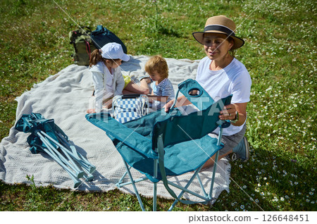 Family Enjoying a Picnic Outdoors in a Sunny Meadow Family Enjoying a Picnic Outdoors in a Sunny Meadow 126648451
