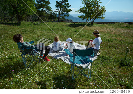Family Enjoying a Scenic Mountain Picnic During National Picnic Month Under Clear Blue Skies 126648459
