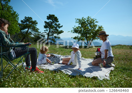 Family Enjoying a Picnic Outdoors on a Sunny Day in Nature Family Enjoying a Picnic Outdoors on a Sunny Day in Nature 126648460