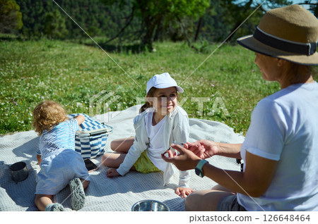 Family Enjoying a Relaxing Picnic Outdoors in a Picturesque Mountain Setting Family Enjoying a Relaxing Picnic Outdoors in a Picturesque Mountain Setting 126648464