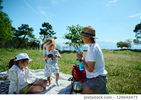 Family Enjoying a Relaxing Picnic in Nature During a Sunny Day Family Enjoying a Relaxing Picnic in Nature During a Sunny Day 126648473