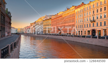 Russia, St. Petersburg, the picturesque Moika river embankment at sunset, the colored facades of houses and their reflection on the water, the beginning of river navigation without tourist boats 126648500
