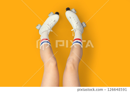 Roller skating fun with retro white skates and striped socks on vibrant orange background Roller skating fun with retro white skates and striped socks on vibrant orange background 126648591