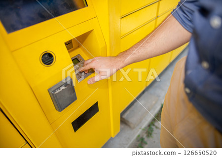 The User Interacting with the StateoftheArt Yellow Delivery Locker for the Package Pickup The User Interacting with the StateoftheArt Yellow Delivery Locker for the Package Pickup 126650520
