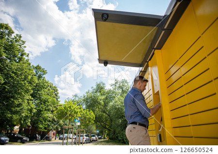Modern Convenience A man interacting with a Yellow Smart Locker Station in the city Modern Convenience A man interacting with a Yellow Smart Locker Station in the city 126650524