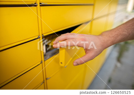 Hand Opening the Bright Yellow Mailbox Slot for Receiving Packages and Mail Items Hand Opening the Bright Yellow Mailbox Slot for Receiving Packages and Mail Items 126650525