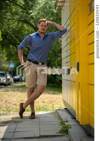 A Stylish Man Posing Outdoors in Trendy Summer Fashion with Vibrant Elements Around Him A Stylish Man Posing Outdoors in Trendy Summer Fashion with Vibrant Elements Around Him 126650543