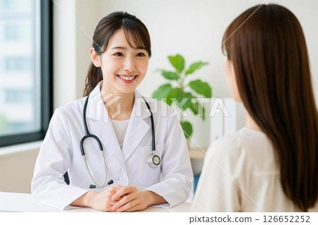 一位微笑的年輕女醫生在檢查期間面對病人 126652252