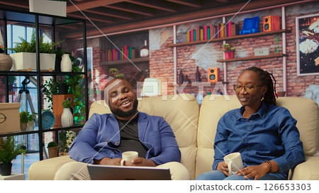 Young couple enjoys a quiet evening at home with warm drinks and sharing stories, serene quiet moments. Partners engaging in laughter and storytelling, relaxation and positive vibes. Camera A. 126653303