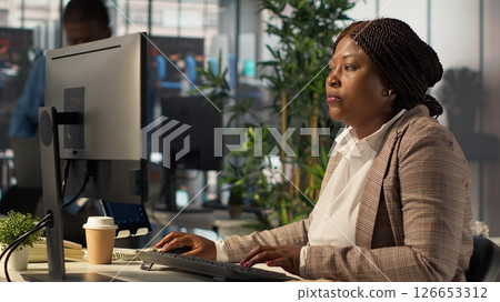 Team of business associates discuss about a project focused on financial growth, evaluating resource allocation and performance metrics. Black staff achieve objectives effectively. Camera A. 126653312
