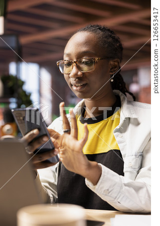 Upbeat woman at home browsing internet on mobile phone, researching information online. Relaxed person in apartment using search engine on smartphone device to find relevant info 126653417