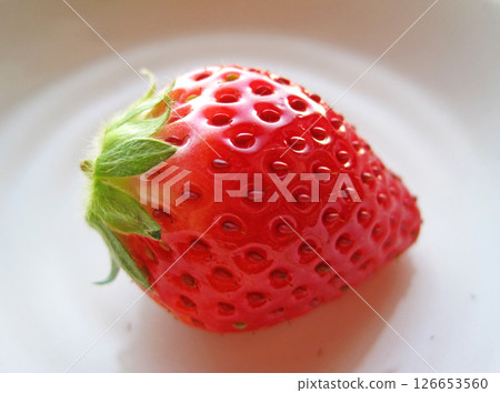 A single strawberry with stem on a plate A single strawberry with stem on a plate 126653560