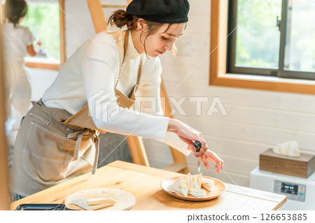 三明治,穿著圍裙的年輕亞洲女人正在做熱三明治 三明治,穿著圍裙的年輕亞洲女人正在做熱三明治 126653885