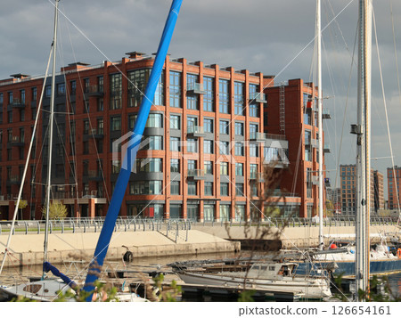 A stunning and modern apartment complex located on the waterfront, featuring sailing yachts nearby A stunning and modern apartment complex located on the waterfront, featuring sailing yachts nearby 126654161